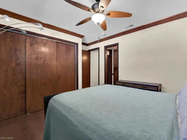 Bedroom featuring ornamental molding, ceiling fan, and dark wood-type flooring