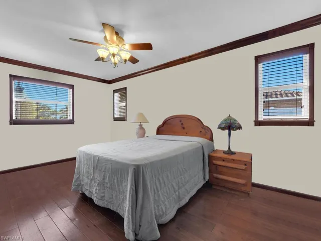 Bedroom with ceiling fan, dark hardwood / wood-style flooring, and ornamental molding
