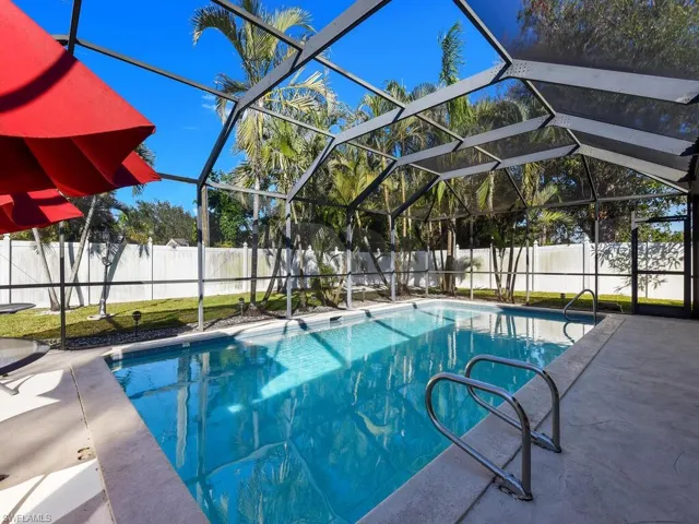 View of pool with glass enclosure and a patio