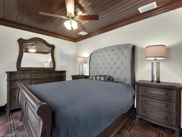Tiled bedroom with ceiling fan, wooden ceiling, and ornamental molding