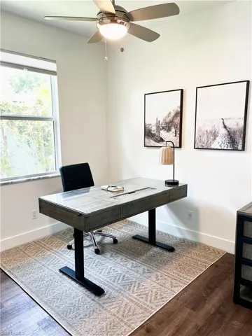 Very bright Office space with dark wood-type flooring and ceiling fan