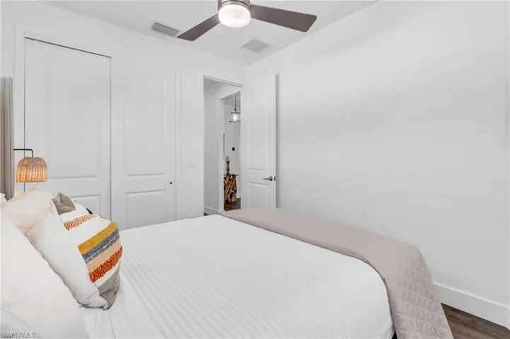Bedroom with dark wood-type flooring, ceiling fan, and a closet