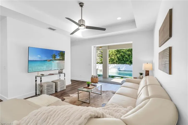Living room featuring hardwood / wood-style flooring, ceiling fan, and a tray ceiling