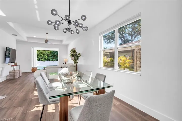 Dining space with a new notable modern chandelier, plenty of natural light, and dark wood-type flooring