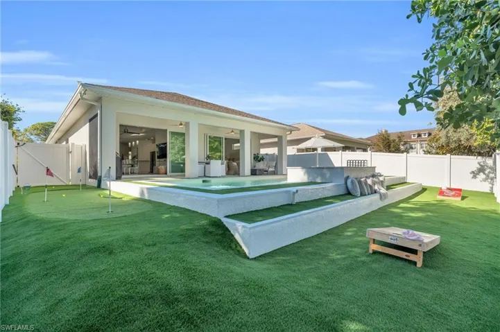 Back of house featuring a corn hole or bocce area with built in bench for watching the games