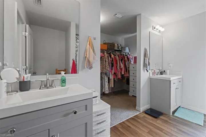 Bathroom featuring two vanities, wood finished floors, and a spacious closet