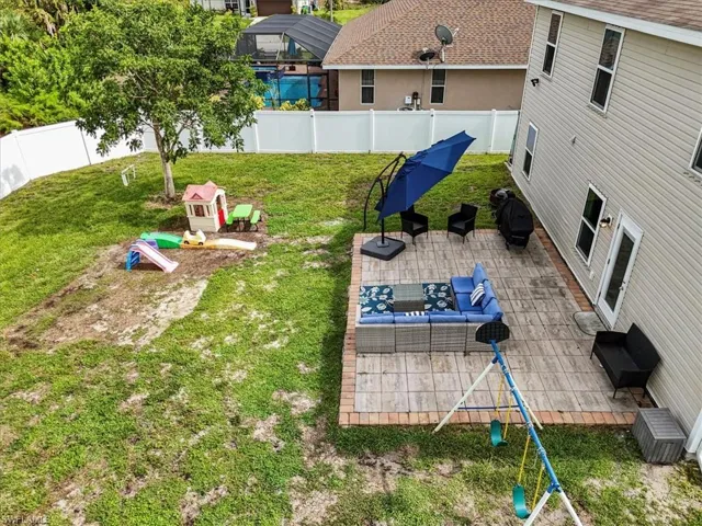 Fenced backyard featuring a playground and a patio