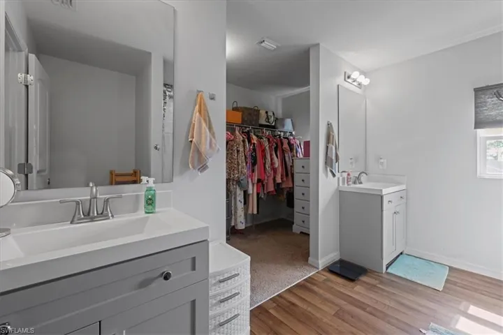 Full bath featuring two vanities, wood finished floors, and a walk in closet