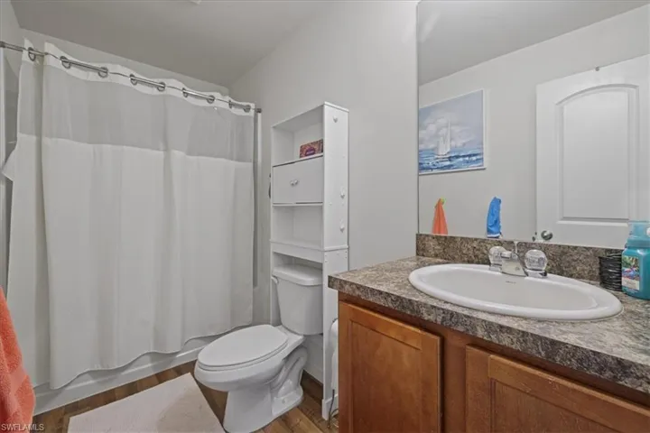 Full bath featuring vanity, wood finished floors, and shower / tub combo with curtain