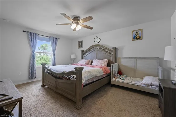 Carpeted bedroom featuring ceiling fan and baseboards
