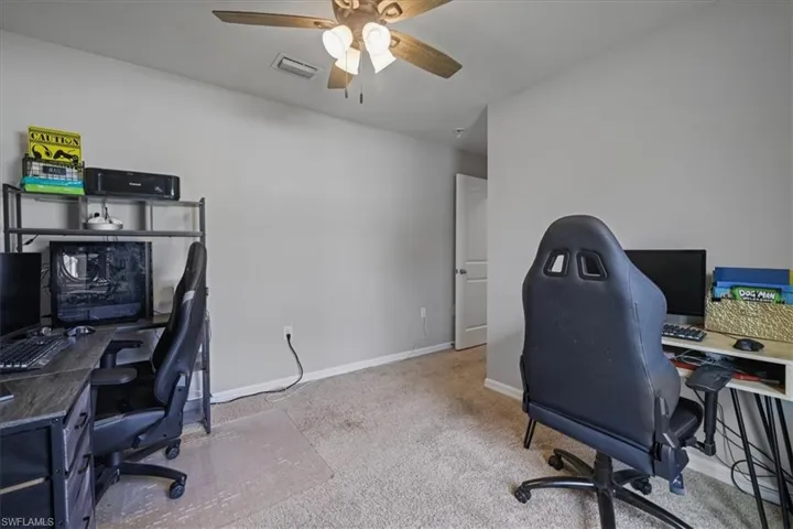 Carpeted office featuring ceiling fan and baseboards