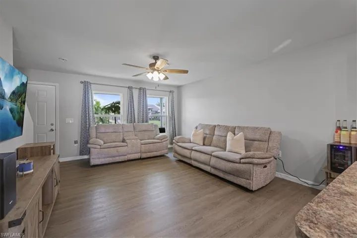 Living room featuring dark wood-style floors and a ceiling fan