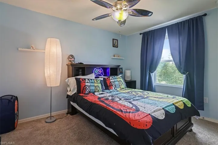 Carpeted bedroom with baseboards and a ceiling fan