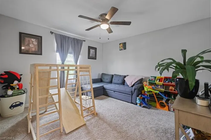 Living area with a ceiling fan and carpet