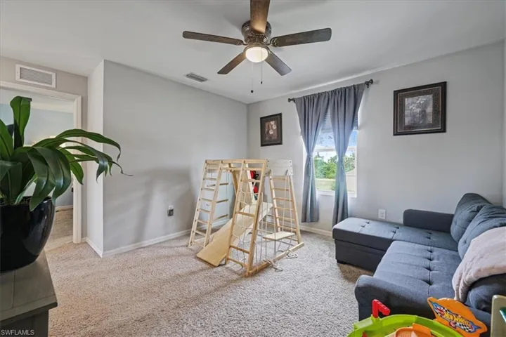 Carpeted living area with baseboards and ceiling fan