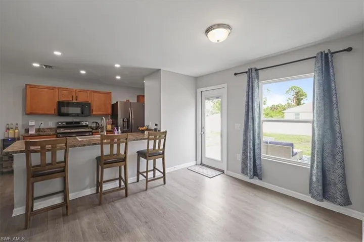 Kitchen with stainless steel appliances, a kitchen bar, light wood-style floors, recessed lighting, and brown cabinetry
