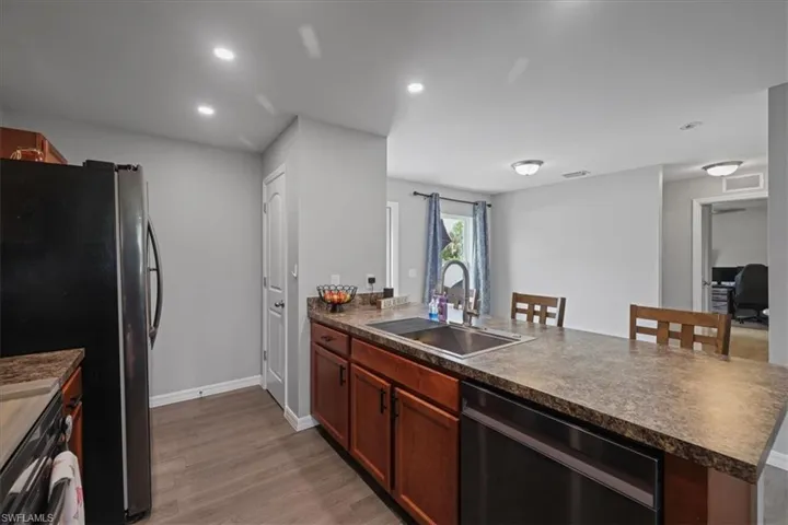 Kitchen with dishwasher, a peninsula, dark countertops, light wood-style floors, and recessed lighting