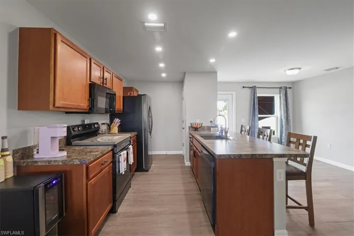 Kitchen with black appliances, a breakfast bar, dark countertops, a peninsula, and light wood-style floors