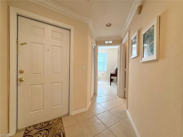 Hall featuring ornamental molding and light tile patterned flooring