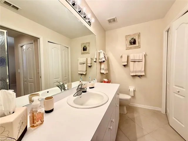 Bathroom featuring vanity, a closet, and light tile patterned floors
