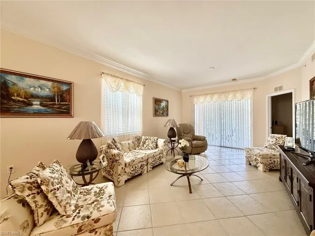 Living room with crown molding and light tile patterned flooring