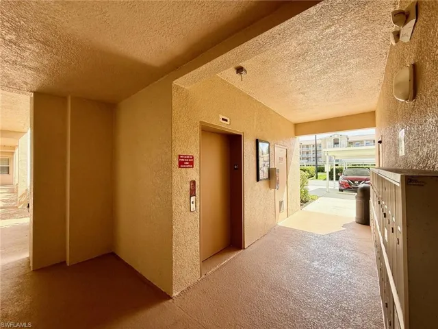 Corridor featuring a textured wall, a textured ceiling, elevator, and carpet