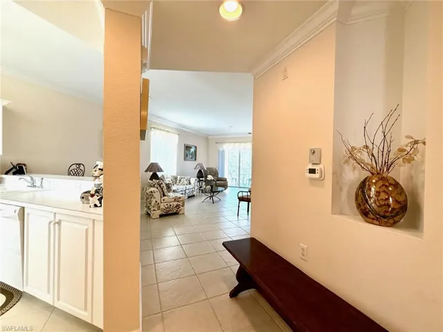Corridor with ornamental molding, light tile patterned floors, and recessed lighting