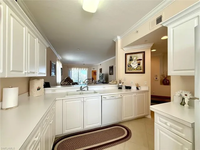 Kitchen featuring crown molding, white cabinets, light countertops, dishwasher, and light tile patterned flooring