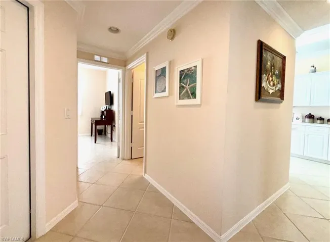 Corridor featuring ornamental molding and light tile patterned flooring
