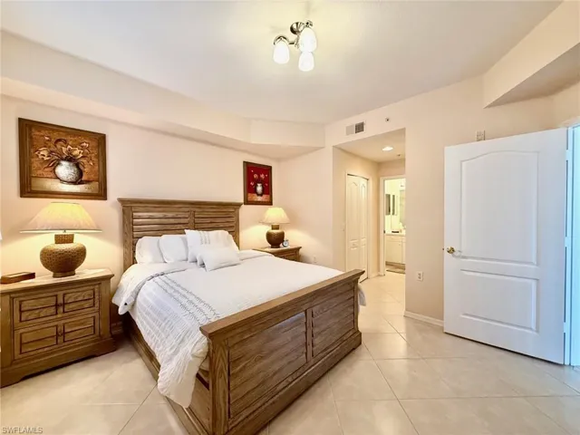 Bedroom with a closet, light tile patterned floors, and ensuite bath