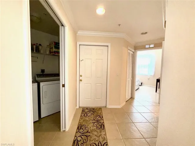 Corridor featuring ornamental molding, light tile patterned floors, independent washer and dryer, and recessed lighting