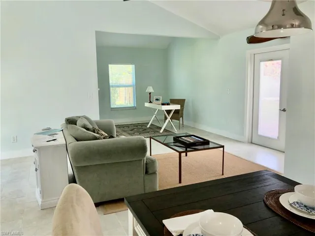 Living room featuring lofted ceiling, light tile patterned floors, and baseboards