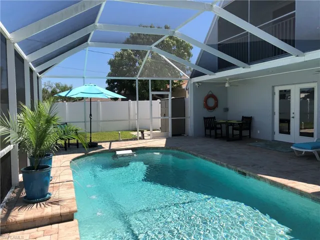 View of swimming pool with french doors, a patio area, ceiling fan, fence, and a lanai