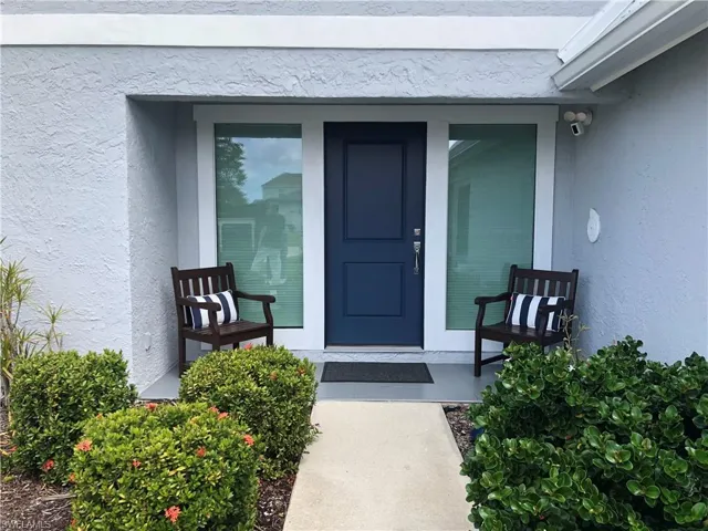 View of exterior entry featuring stucco siding and covered porch