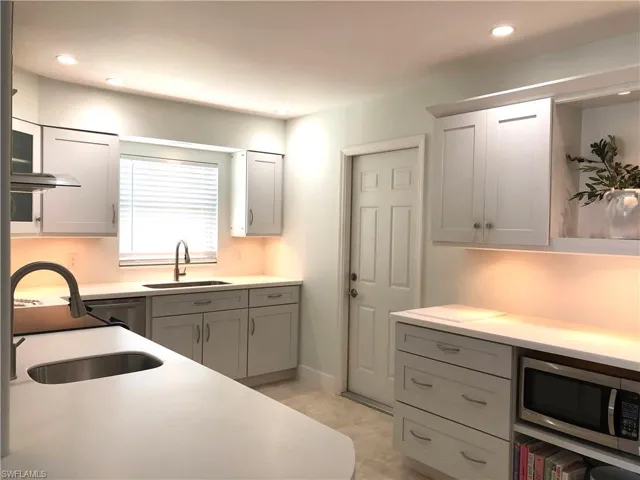 Kitchen with a sink, stainless steel microwave, light countertops, recessed lighting, and gray cabinets