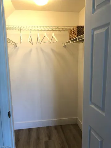 Walk in closet with dark wood-type flooring