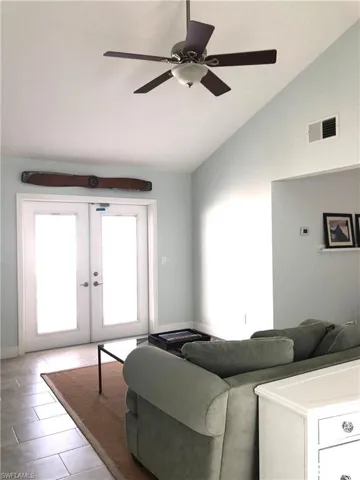 Living area featuring french doors, ceiling fan, baseboards, and high vaulted ceiling