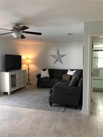 Living area with light tile patterned floors, baseboards, and a ceiling fan