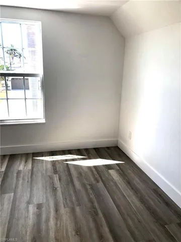 Additional living space with wood finished floors, baseboards, and lofted ceiling