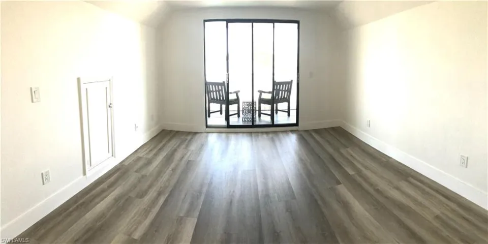 Unfurnished room with baseboards, dark wood finished floors, and lofted ceiling