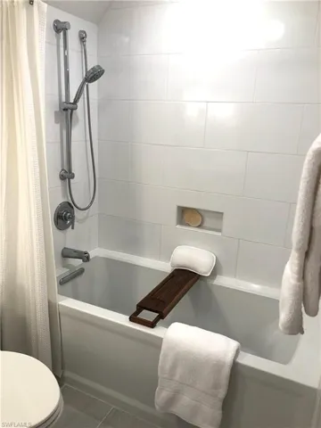 Bathroom featuring shower / bathtub combination with curtain and toilet