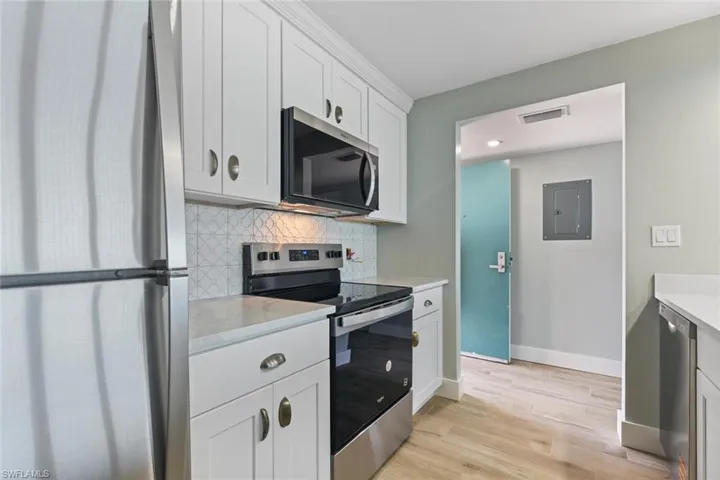 Kitchen featuring light wood-style floors, tasteful backsplash, electric panel, visible vents, and appliances with stainless steel finishes