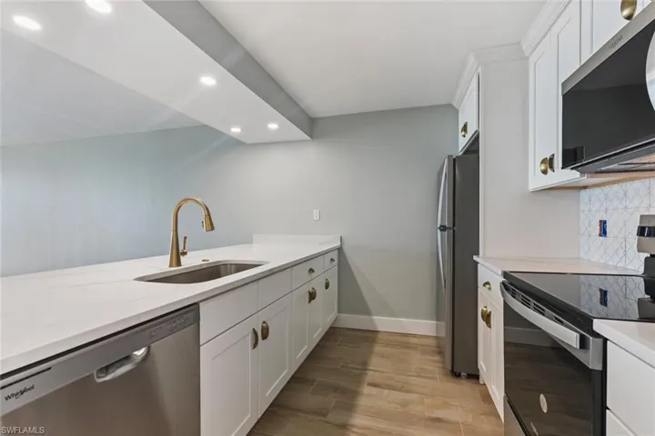 Kitchen with white cabinets, recessed lighting, a sink, stainless steel appliances, and backsplash