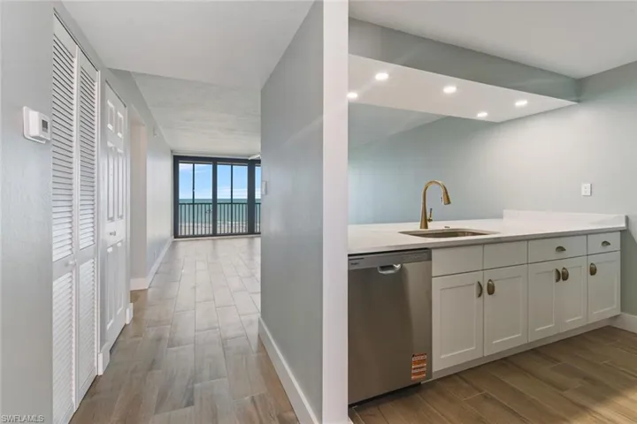 Kitchen featuring dishwasher, baseboards, a sink, and wood finished floors