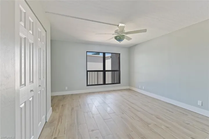 Unfurnished room featuring baseboards, light wood-type flooring, a ceiling fan, and a textured ceiling
