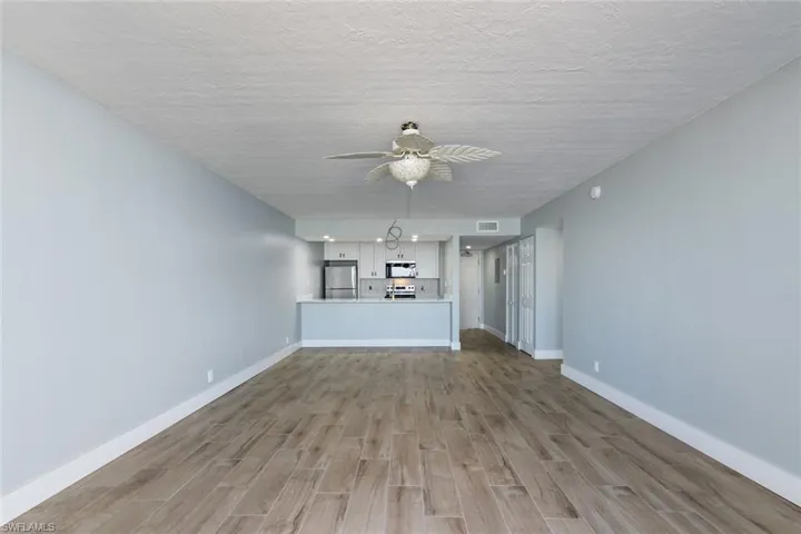Unfurnished living room with baseboards, a textured ceiling, a ceiling fan, light wood-style floors, and visible vents