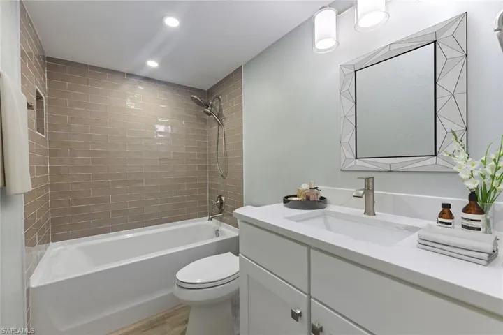 Bathroom featuring tub / shower combination, vanity, recessed lighting, toilet, and wood finished floors