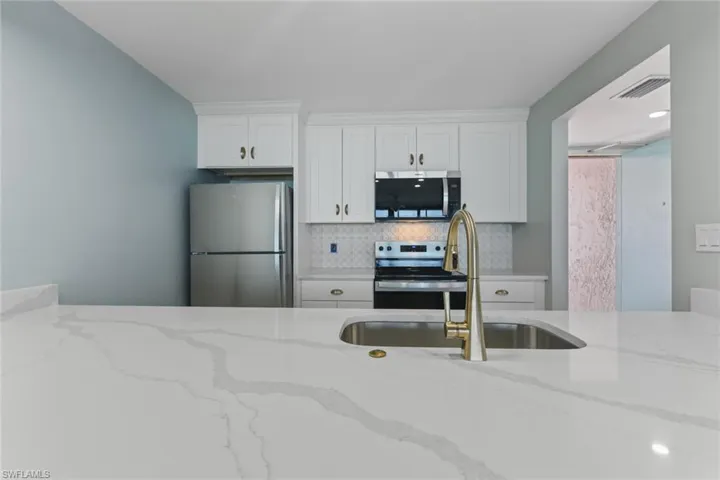 Kitchen featuring white cabinetry, appliances with stainless steel finishes, a sink, and backsplash