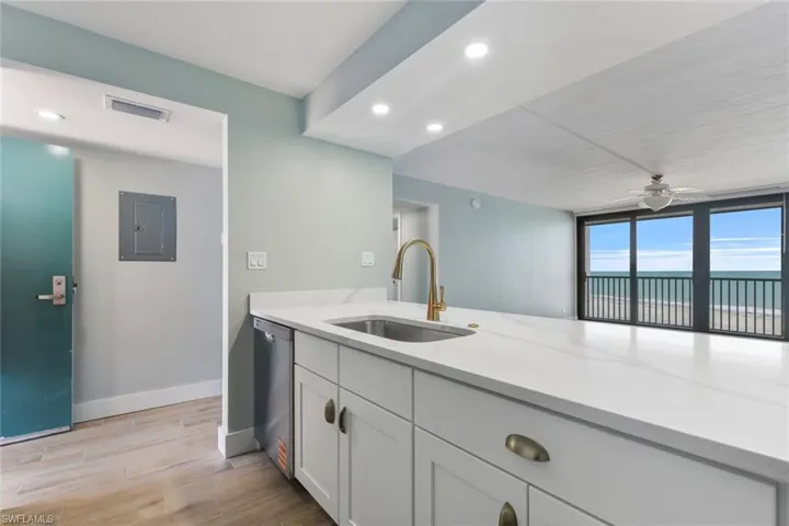 Kitchen featuring electric panel, light stone countertops, visible vents, stainless steel dishwasher, and a sink