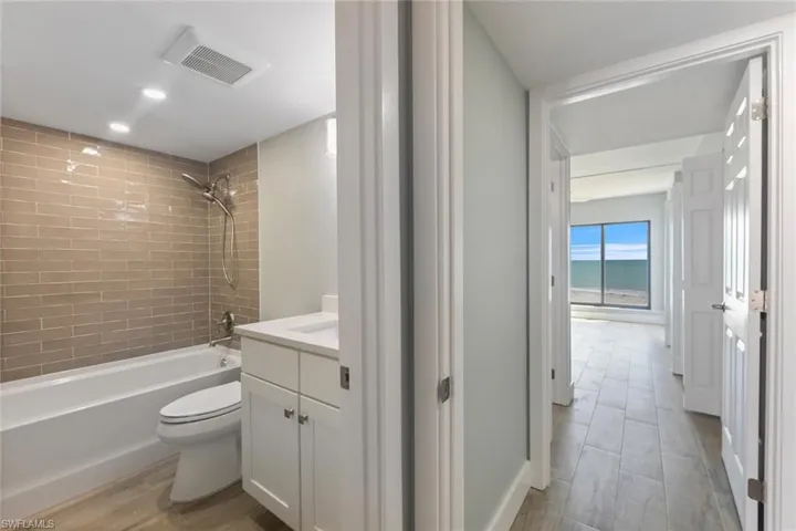 Bathroom with vanity, toilet, visible vents, tub / shower combination, and wood finished floors